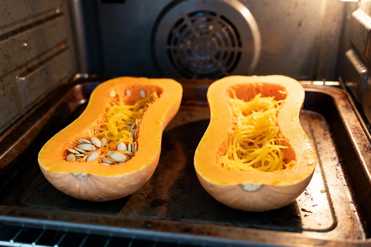 Deux moitiés de courge spaghetti en cuisson au four avec graines visibles